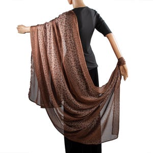 May include: A brown and black patterned sheer scarf with a flowing design.
