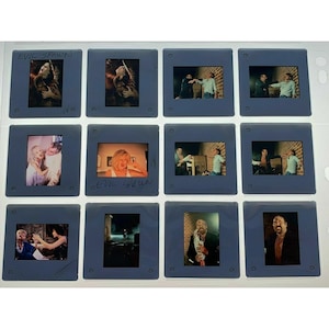 May include: A collection of twelve film slides in blue frames. The slides feature various scenes, including people in different settings, with some slides labeled "EVIL SPAWN". The images are in various colors.