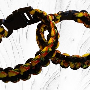 May include: Two black and yellow paracord bracelets with a red stripe. One bracelet has a black plastic clasp.