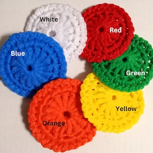 May include: Six crocheted circles in different colors: white, blue, red, green, yellow, and orange. Each circle has a hole in the center.