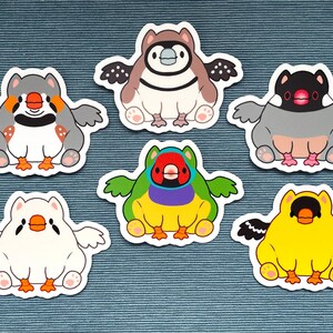 Könnte beinhalten: Eine Sammlung von sieben Aufklebern mit Cartoon-Vögeln. Jeder Aufkleber zeigt ein anderes Vogeldesign mit verschiedenen Farben, darunter Grau, Braun, Gelb, Grün und Weiß. Die Vögel haben Flügel und sitzen. Die Aufkleber befinden sich auf einem blauen Hintergrund.