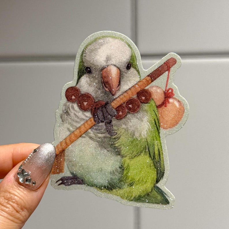 Puede incluir: Una pegatina brillante con un p&aacute;jaro de dibujos animados con plumas verdes y blancas, sosteniendo un palo marr&oacute;n con una bolsa roja. El p&aacute;jaro tiene un pico marr&oacute;n y lleva un collar de cuentas marrones. La pegatina tiene un acabado brillante.