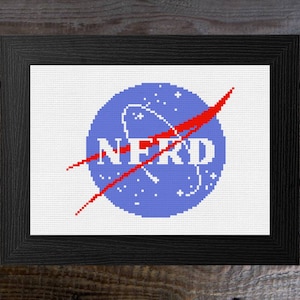 May include: A blue and red cross-stitch embroidery of the NASA logo, but with the word "NERD" in place of "NASA".