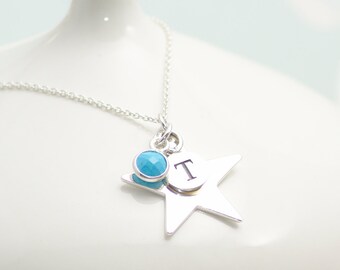 May include: A silver necklace with a star charm, a turquoise gemstone, and the letter "T" on the star.