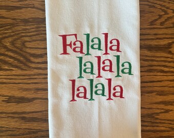 May include: White kitchen towel with the words "Falala lalala lalala" embroidered in red and green.