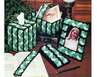 May include: A set of green and black plastic canvas crafts including a tissue box cover, a picture frame, a bookmark, and a small rectangular box. The crafts feature a braided pattern with green and white yarn.