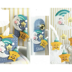 May include: A set of three blue and white canvas needlepoint projects featuring a sleeping moon and stars with smiling faces. The projects include a tissue box cover, a door hanger, and a mobile.