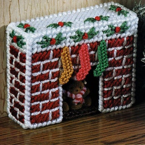 May include: A white and red brick fireplace with a white mantel decorated with green holly and red berries. A brown teddy bear with a red and white striped scarf is sitting in the fireplace opening. There are four stockings hanging from the mantel, one yellow, one red, one green, and one gold.