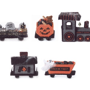 Puede incluir: Cinco vagones de tren con temática de Halloween hechos de lona de plástico. Los vagones están decorados con fieltro naranja, negro y gris. Los vagones incluyen un vagón con forma de calabaza, un vagón con un fantasma, un vagón con un osito de peluche, un vagón con lápidas y un vagón con una campana y las palabras "Spooky Express".