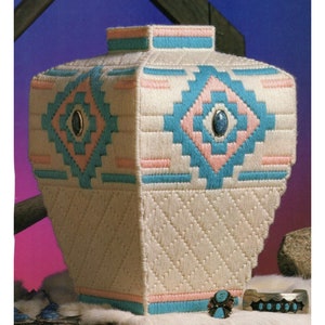 May include: A white ceramic vase with a geometric design in pink, blue, and turquoise. The vase has a turquoise trim and features turquoise stones.