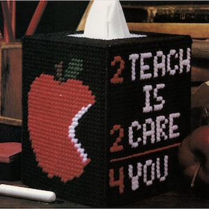 May include: Black tissue box cover with a red apple and the text "2 TEACH IS 2 CARE 4 YOU" in white.