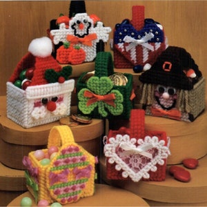 May include: A collection of eight small, colorful, plastic canvas baskets with various holiday themes. The baskets are filled with candy and other small items. The themes include Santa Claus, a ghost, a shamrock, a heart, a scarecrow, a pumpkin, an Easter egg, and an American flag.