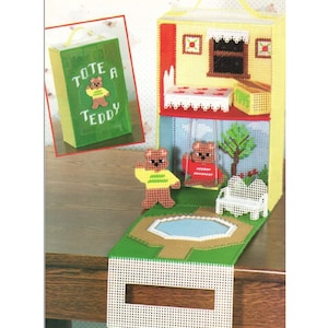 Pode incluir: Uma bolsa verde com as palavras "tote a teddy" na frente. A bolsa está ao lado de uma casa de bonecas em miniatura com um telhado branco e um gramado verde. Dois ursos de pelúcia estão sentados em um balanço no quintal. A casa de bonecas tem uma porta vermelha e uma janela branca.