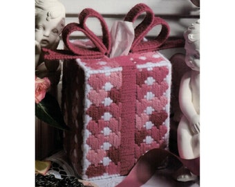 May include: A pink and white tissue box cover with a pink bow. The cover is made of yarn and has a heart pattern.