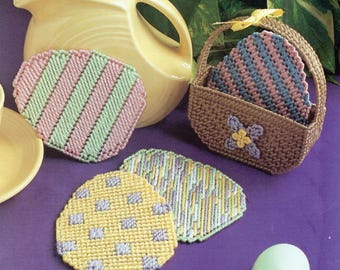 May include: Set of four crocheted Easter egg-shaped coasters in pink, green, yellow, and gray. The coasters are in a basket with a brown and white crocheted design. The basket has a flower design on the front.