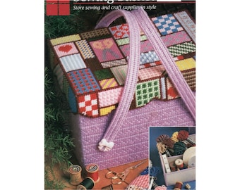 May include: A lavender sewing box with a patchwork design on the lid, featuring various colorful geometric patterns. The box has a matching handle and a small bow closure. The image also includes spools of thread and scissors.