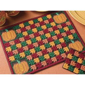 May include: A set of two needlepoint placemats featuring a checkered pattern of green, red, orange, and yellow leaves with pumpkin accents.