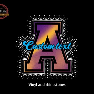 May include: A purple and orange letter A with a black outline, surrounded by white rhinestones. The letter is in a varsity style font. The text "Custom text" is written in blue cursive above the letter. The text "Vinyl and rhinestones" is written below the letter.