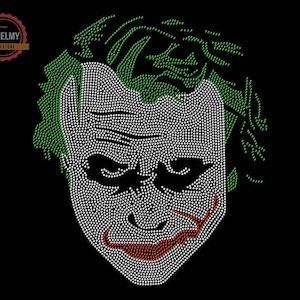 May include: A close-up of a rhinestone design of the Joker's face. The design is made up of white, green, and red rhinestones. The Joker's face is a classic image from the Batman comics and movies.