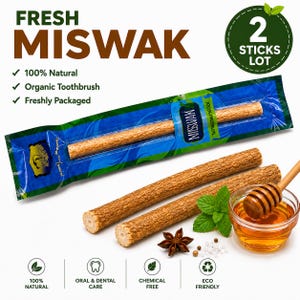 May include: Two brown, textured Miswak sticks, one inside a blue and green plastic wrapper labeled "FRESH MISWAK" and "2 STICKS LOT," and one loose next to a small glass bowl of honey with a wooden dipper, a mint sprig, and a star anise.