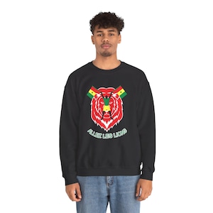 May include: A black crewneck sweatshirt featuring a graphic of a red lion head with a silhouette of a person holding two Senegal flags above it. Below the lion, the text "ALLEZ LES LIONS" is printed in white letters with a green outline.