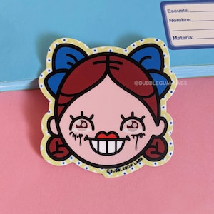 May include: A sticker of a cartoon girl with red hair, blue bows, and a big smile. Her eyes are wide open and she has red lipstick. The sticker is on a pink background. The text "BUBBLEGUM LABS" is on the sticker.