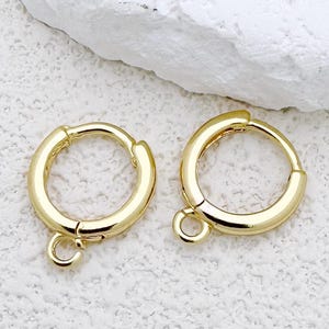 Puede incluir: Un par de pendientes de aro dorados con un pequeño aro de unión unido a cada aro.