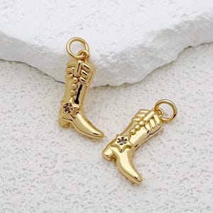 May include: Two gold-toned cowboy boot charms with a single rhinestone on each boot.