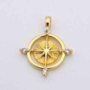 May include: Gold compass pendant featuring a starburst design with clear crystal accents.