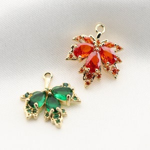 May include: Two gold-tone leaf-shaped charms with red and green crystal accents. The charms are perfect for adding a touch of sparkle to jewelry projects.