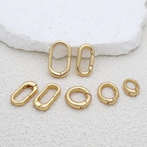 May include: A set of six gold-toned metal clasps in various sizes and shapes. The clasps are oval and round, and some have a spring-loaded closure.