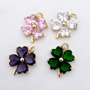 Può includere: Quattro ciondoli a forma di quadrifoglio dorati con accenti di cristallo di diversi colori. I ciondoli sono rosa, bianco, viola e verde.