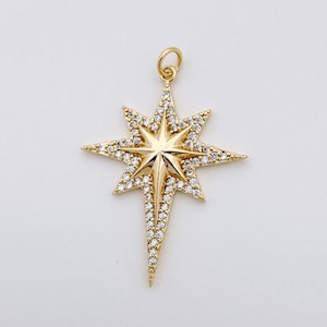 May include: A gold-tone star pendant with clear crystal accents. The star has a pointed tip and is set with small, sparkling crystals.