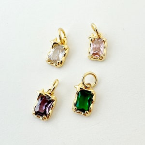 以下が含まれることがあります： 異なる色の宝石が付いた金のチャームが4つ。各チャームには星の形と長方形の宝石が施されています。宝石は透明、ピンク、緑、紫です。
