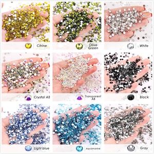 May include: Assortment of round, flat-back rhinestones in various colors, including citrine, olive green, white, crystal AB, transparent AB, black, light blue, aquamarine, and gray.