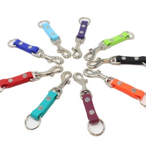 May include: Assortment of ten colorful keychains with silver swivel clips and key rings. The keychains are made of a rubber-like material and have two silver dots on each.