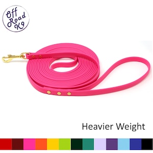 May include: A hot pink dog leash coiled in a circle, featuring a gold-toned metal swivel snap hook and three gold-toned rivets. The text Off Road K9 is in the top left corner, and the text Heavier Weight is in the bottom right corner.
