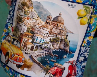 May include: A colorful fabric with a watercolor illustration of a coastal town with a church, a yellow car, a red scooter, and lemons. The fabric has a blue and white border with a floral pattern. The text "MALJA" is printed on the fabric.
