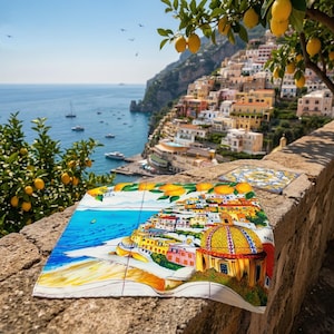 May include: A colorful tile set featuring a coastal Italian town scene with a blue sea, yellow buildings, and a golden-domed church. The tiles are displayed outdoors with a scenic view of the coast, lemon trees, and the sea.