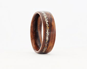 May include: A dark brown wooden ring with a thin band of white and gold inlay.