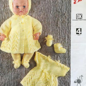 Puede incluir: Un patrón de tejido para un vestido y un abrigo amarillos para muñeca. El patrón es para un hilo de tejido doble de 4 hebras y se llama "Emu" con el número 6688.