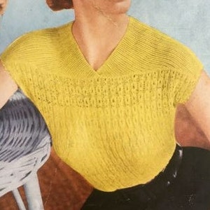 May include: A yellow knitted sleeveless top with a V-neck and a delicate openwork pattern.