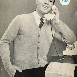 May include: A man wearing a gray cardigan sweater with a white shirt and a dark tie is on the phone. He is sitting at a desk with a phone and a notepad. The number 208 is visible in the top right corner of the image.