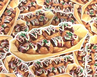 Op de afbeelding: Een close-up van meerdere stickers met een cartoonillustratie van takoyaki, een Japans straatvoedsel, in een papieren bakje. De takoyaki zijn bedekt met saus, mayonaise en lente-uitjes.