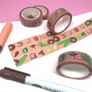 Puede incluir: Cuatro rollos de cinta washi con un diseño de comida pixelado. La cinta presenta champiñones, huevos, tocino, fideos y otros alimentos sobre un fondo marrón claro.