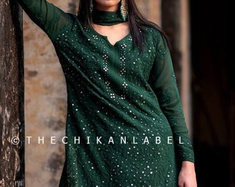 May include: A dark green long-sleeved kurta with silver embroidery and sequins. The kurta is paired with matching pants. The model is wearing a dark green dupatta with silver embroidery and sequins.