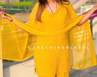May include: A bright yellow salwar kameez ensemble. The outfit includes a tunic top, wide-legged pants, and a sheer scarf. The outfit is embroidered and the text "@THECHIKANLABEL" is visible.