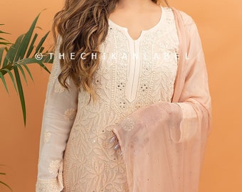 May include: A peach-colored chikankari kurta with intricate embroidery and sequins. The kurta has a V-neckline and long sleeves. The model is wearing a matching peach-colored dupatta.