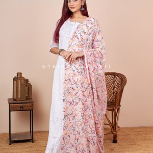 Pu&ograve; includere: Una kurta bianca ricamata con un dupatta ricamato con fiori rosa. La kurta ha una scollatura rotonda e maniche a tre quarti. Il dupatta &egrave; trasparente e presenta un delicato motivo floreale.