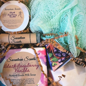 May include: A gift box filled with bath and body products. Includes a round container of body butter, a tube, a bar of soap, and a loofah. The products are labeled "Seventeen Scents Black Raspberry Vanilla". The soap is labeled "Natural Goats Milk Soap".